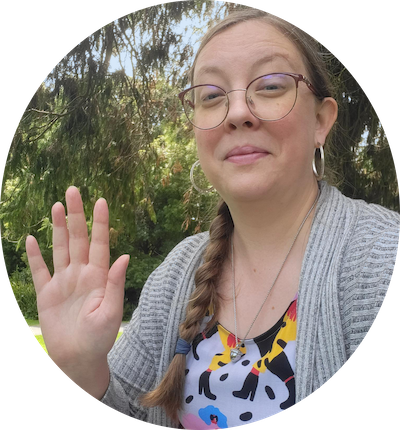 Portrait image of Katherine McGonigle waving, while on a lovely picnic.